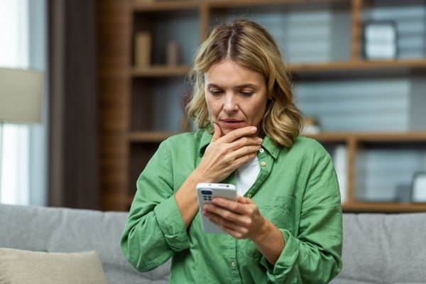 A worried senior woman holding her phone