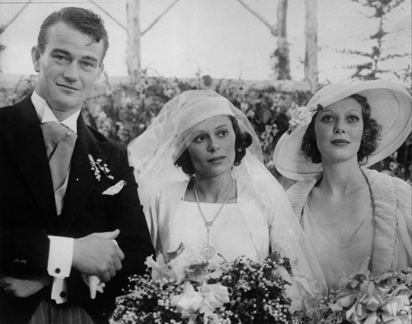 Film actor John Wayne on his wedding day with his wife Josephine Saenz and Loretta Young.