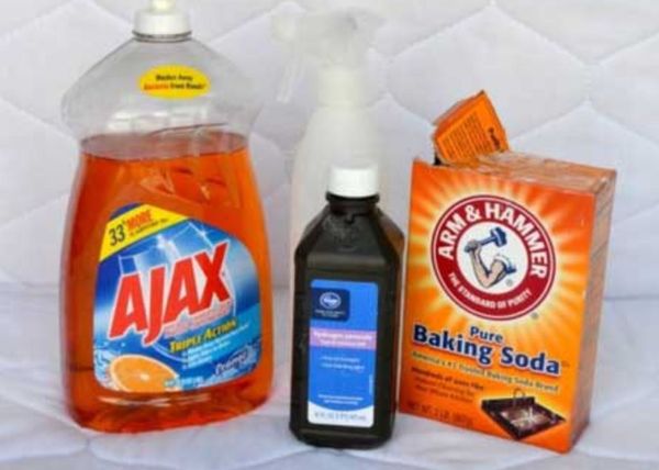 Cleaning supplies to remove mattress stains with a white mattress in the background.