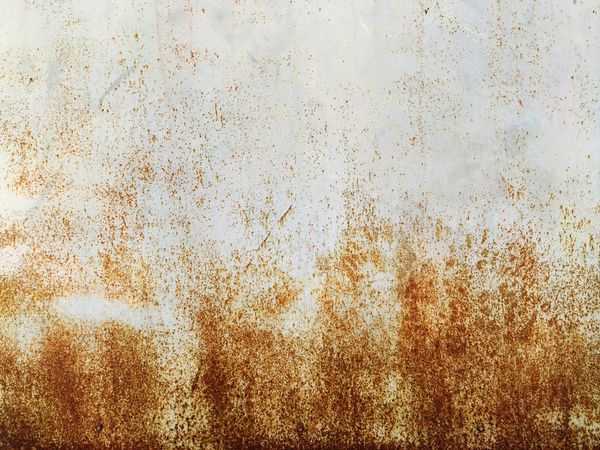 Corroded metal background. Rusted grey painted metal wall. Rusty metal background with streaks of rust. Rust stains. The metal surface rusted spots. Rystycorrosion.